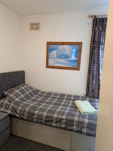 a bed in a room with a picture on the wall at Kettering Town End terrace walking distance to Kettering town in Kettering