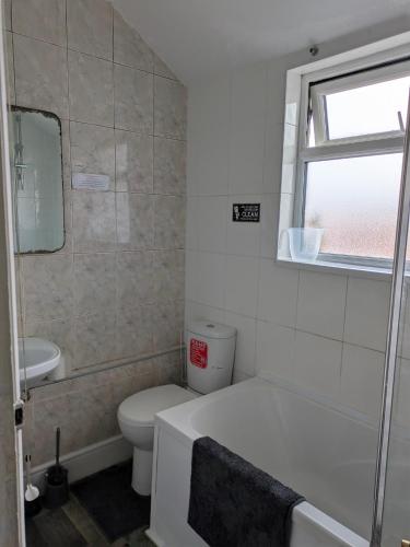 a bathroom with a tub and a toilet and a window at Kettering Town End terrace walking distance to Kettering town in Kettering
