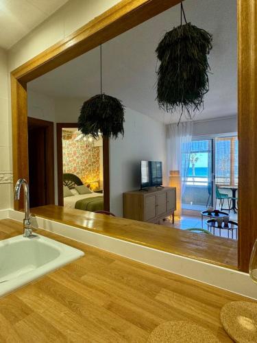 a bathroom mirror with a sink and a living room at Beachfront apartment in El Altet