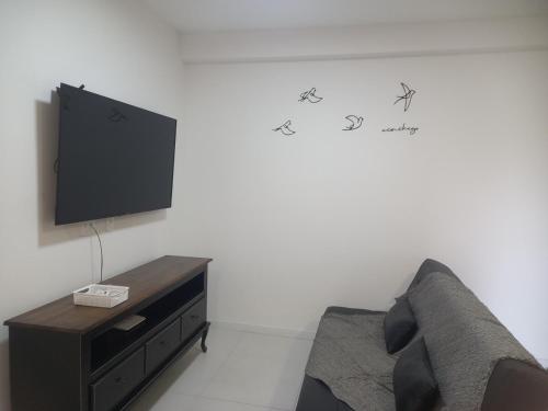 Una sala de estar con un sofá y un televisor en una pared. en Apto com piscina a 150m da Praia!, en Penha