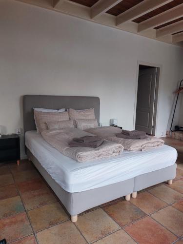 a white bed in a bedroom with a white wall at Landelijk gastenverblijf met zwembad en sauna in het hart van Friesland in Akkrum