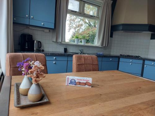 a kitchen table with a book and flowers on it at Luxe gastenverblijf met wellness in het hart van Friesland in Akkrum