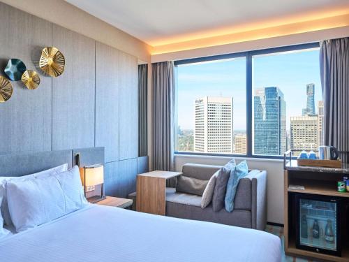 a hotel room with a bed and a couch and a window at Novotel Melbourne Central in Melbourne