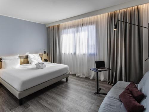 パルマにあるNovotel Parma Centroのベッド1台、ノートパソコン1台(テーブル上)が備わります。