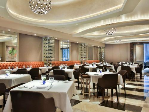 a restaurant with white tables and chairs and wine bottles at Palladio Hotel Buenos Aires - MGallery Collection in Buenos Aires