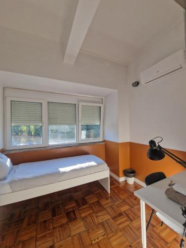 a bedroom with a bed and two windows at Home Carriche in Lisbon