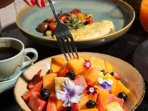uma pessoa a comer um prato de fruta com um garfo em Pullman Lima San Isidro em Lima