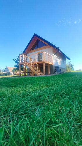 una casa con un campo de hierba delante de ella en Domek Czarnucha, en Augustów