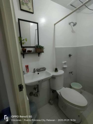 a white bathroom with a toilet and a sink at Serene Home Stay in Puerto Princesa City