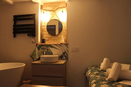 ein Badezimmer mit Waschbecken, Spiegel und Badewanne in der Unterkunft Studio cosy & ses troglos "Chez Evariste" 