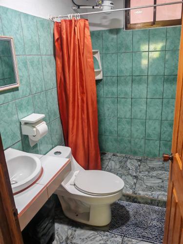 a bathroom with a toilet and a red shower curtain at Casa Caribe in Tortuguero