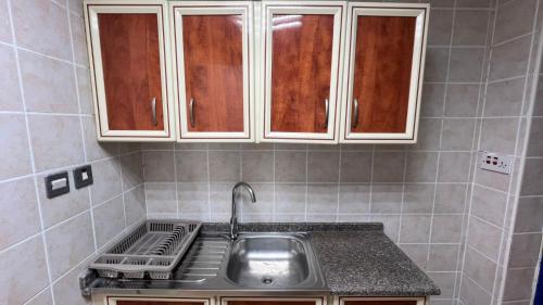 a kitchen with a sink and white cabinets at XD Cozy Apartments in Abu Dhabi