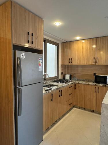 a kitchen with a stainless steel refrigerator and wooden cabinets at Imsouane Sea surf Camp in Imsouane