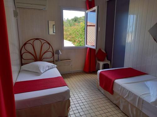 Una habitación de hotel con dos camas y una ventana. en Résidence les hibiscus 4, en Bouillante
