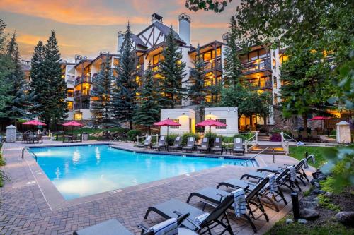 a large pool with chairs and umbrellas in front of a hotel at Montaneros in Vail in Vail