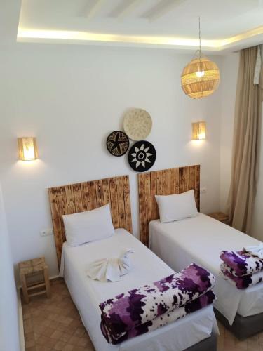 a bedroom with two beds and a clock on the wall at Igiwano guest house in Essaouira