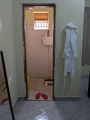 a bathroom with a shower with a robe and red shoes at Masaka Haven in Masaka