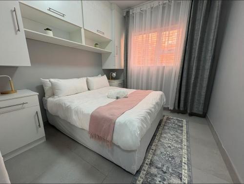 a bedroom with a large bed and a window at Windermere Sands in Gqeberha