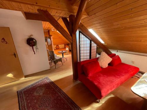 a living room with a red couch in a attic at Schöne Ferienwohnung in Bahnhofsnähe für Urlaub, Studium oder Arbeit in Deggendorf