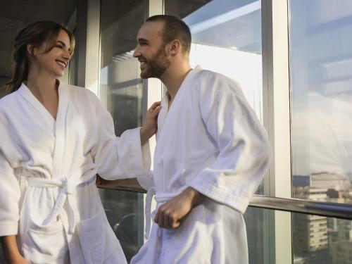 a man and woman in white robes standing in front of a window at Pullman Santiago El Bosque in Santiago