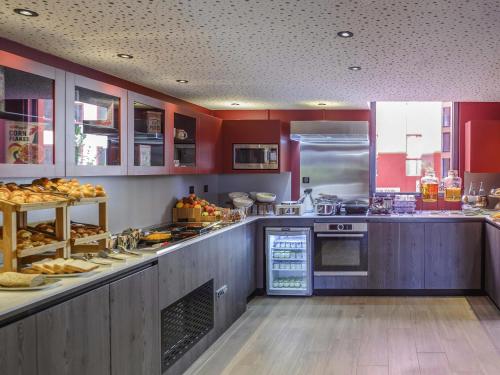 a kitchen with red walls and a counter with food at Novotel Saint-Étienne Centre Gare Châteaucreux in Saint-Étienne