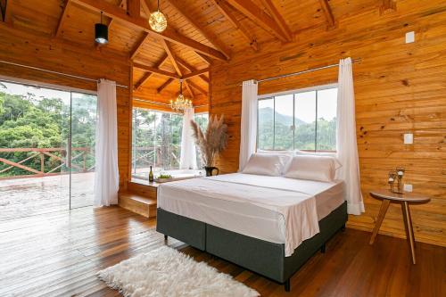 ein Schlafzimmer mit einem Bett in einem Holzzimmer mit Fenstern in der Unterkunft Altos das Araucárias - one place, great moments! in Alfredo Wagner