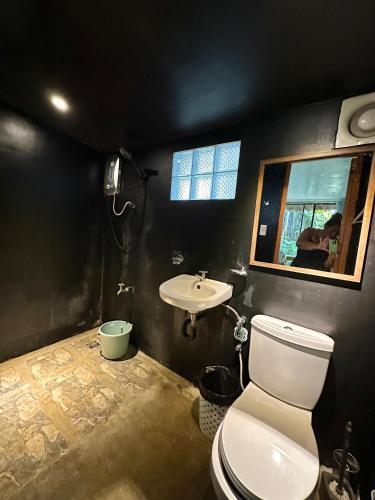 a bathroom with a white toilet and a sink at Paradiso Hostel Siargao in General Luna