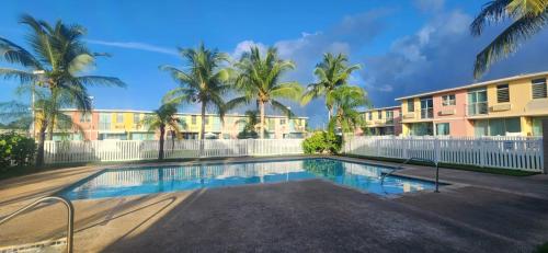 een zwembad voor een gebouw met palmbomen bij Isla Bonita Townhouse - 5 min SJU in Carolina