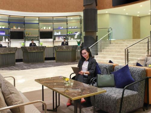 ジャカルタにあるNovotel Jakarta Cikiniのノートパソコンを持ってテーブルに座っている女性