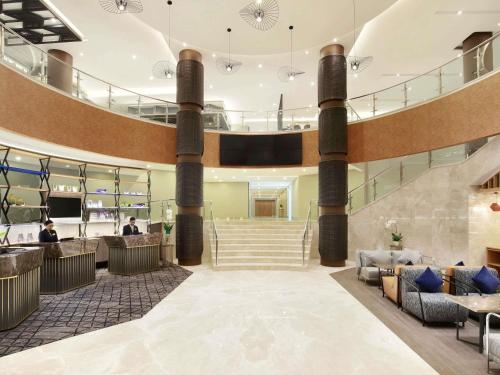 ジャカルタにあるNovotel Jakarta Cikiniのソファと階段のあるホテルのロビー