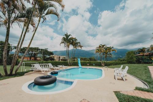 カラルカにあるFinca Hotel La Cabañitaの椅子とヤシの木のあるプール