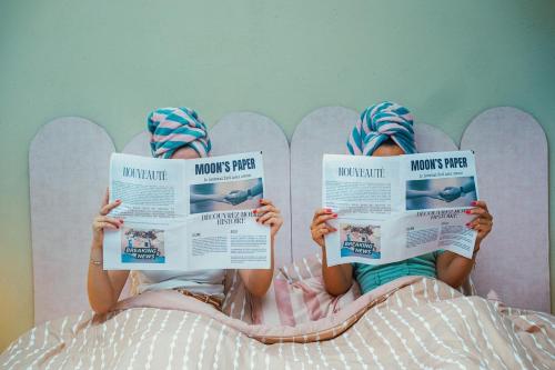 dos niños sentados en una cama leyendo libros en Le Beverly Moon - Private Pool & Spa, en Dinant