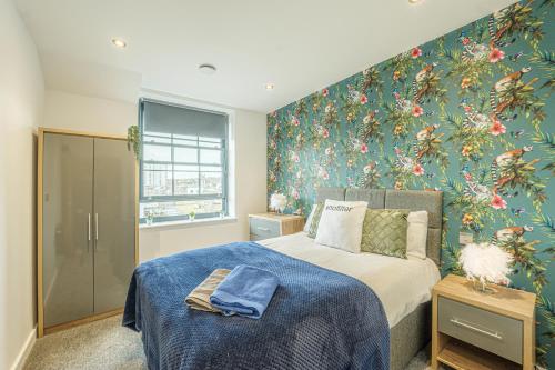 Un dormitorio con una cama con papel pintado floral. en Seaside Apartments Ramsgate, en Ramsgate