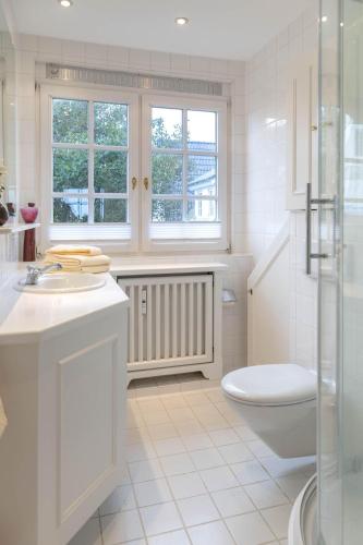 a white bathroom with a toilet and a sink at Heefwai-Wohnung-4 in Morsum