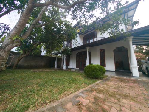 una casa blanca con un árbol en el patio en Bliss Villa-Mirissa, en Kamburugamuwa