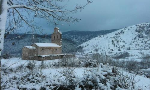 an old building in the snow with a mountain at Villa Flavina in San Vicente del Valle