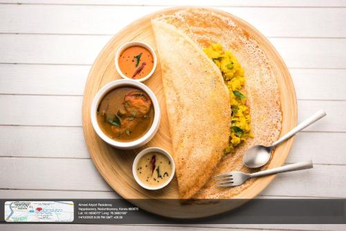a plate of food with a sandwich and two bowls of soup at AIRNEST Airport Residency in Nedumbassery