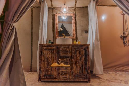 a bathroom with a sink and a mirror and curtains at Sahara Camp Excursions in Merdani