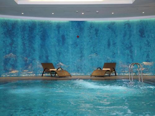 a swimming pool with chairs in a large aquarium at Novotel Bishkek City Center in Bishkek