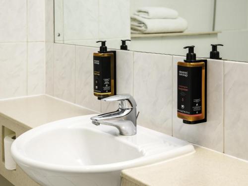 a bathroom sink with two soap dispensers on the wall at The Harlow Hotel By AccorHotels in Harlow