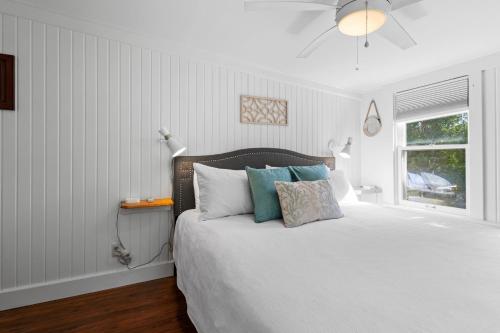 a bedroom with a white bed with pillows and a window at The Old Apartment in Fort Pierce