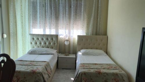 deux lits dans une petite pièce avec une fenêtre dans l'établissement orange room, à Durrës