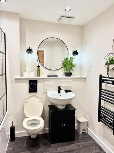 a bathroom with a toilet and a sink and a mirror at Lux Stays - 2BR Leeds City Centre Apartment - Ground Floor with Free Parking in Leeds