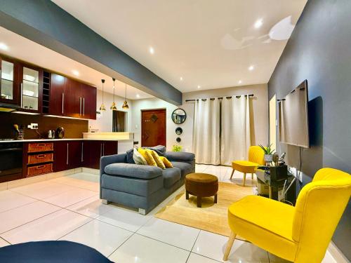 a living room with a blue couch and yellow chairs at Umoya Executive Apartment in Mbabane