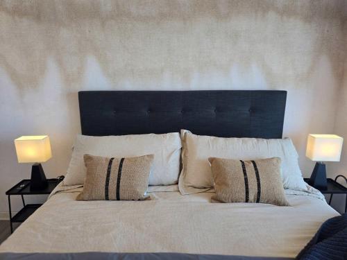 a bed with white pillows and two lamps at HOM I Ideal Depto 2D2B Frente al Mall Antofagasta in Antofagasta