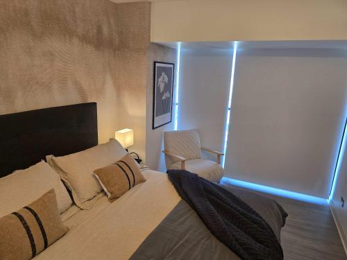a bedroom with a bed and a chair in it at HOM I Ideal Depto 2D2B Frente al Mall Antofagasta in Antofagasta