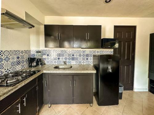a kitchen with a black refrigerator and a sink at Espacio perfecto para 3 con alberca in Chuburná de Hidalgo
