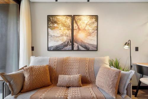 ein Wohnzimmer mit einem Sofa und zwei Gemälden an der Wand in der Unterkunft Condomínio Residencial e Comercial YOU in Canela