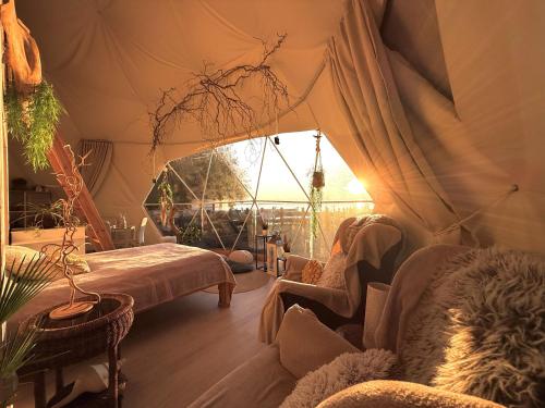 a bedroom with a tent with a bed and a chair at Romantic Dome - Private Hot Tube, Sauna & Lake view in Wapnica
