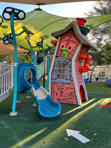 a playground with a small house and a slide at Rose Suite in Caesarea
